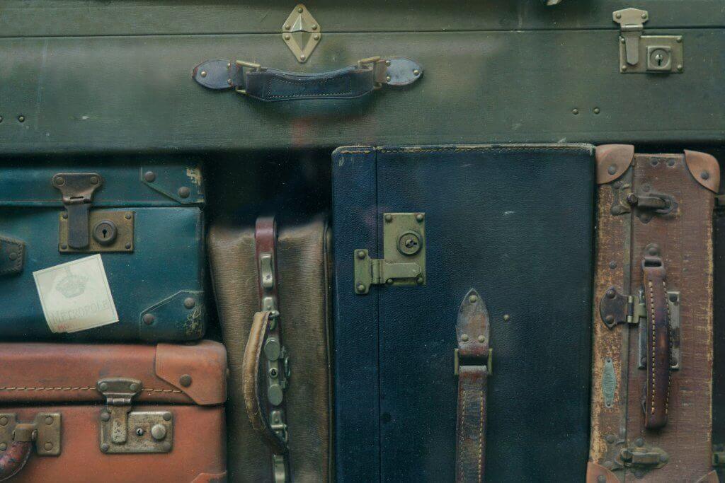 Stack of vintage suitcases in various colors and conditions”